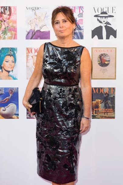 Alexendra Shulman in front of a wall of Vogue magazine front covers going back to the 1910s